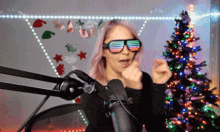 a woman wearing sunglasses and a microphone in front of a christmas tree .