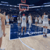 a group of female basketball players standing on a court with one wearing the number 10
