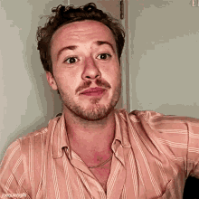 a man with a beard wears a striped shirt and a necklace