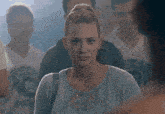 a woman in a blue cardigan is standing in a crowd of people