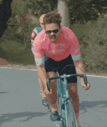 a man riding a bike wearing a pink shirt that says gdf