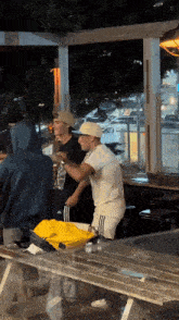 a man in a white shirt is sitting at a picnic table with other people