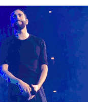 a man with a beard is standing on a stage with his hand on his forehead