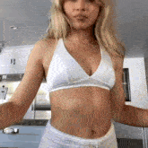 a woman in a white bra and white shorts is dancing in a kitchen .