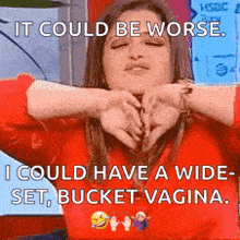 a woman in a red sweater is making a funny face with her hands around her face .