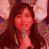 a woman is holding a microphone in her hand and smiling .