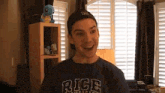 a man wearing a rice shirt and a hat is smiling