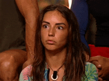 a woman wearing a necklace with a circle pendant looks surprised
