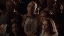 a man in a plaid shirt stands in a crowd