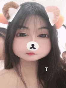 a girl with a teddy bear face on her face and the letter t next to her