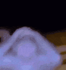 a person is laying on a bed with their hands on their head and a purple light behind them .