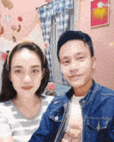 a man and a woman are posing for a picture in front of a pink wall with a picture of balloons on it
