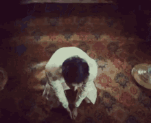 a man in a white jacket is sitting on a rug