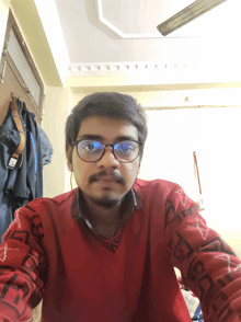 a man wearing glasses and a red sweater with the letter g on the sleeve