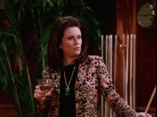 a woman in a leopard print jacket holds a glass of wine and a pool cue