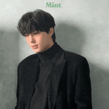 a young man wearing a black turtleneck and a black jacket with the word mint on the bottom