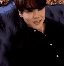 a young man is sitting on a blue couch and looking at the camera .