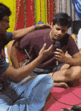 a man is sitting on the floor with a microphone in his hands