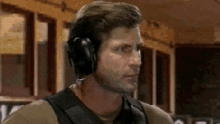 a man wearing headphones is standing in front of a window in a room .