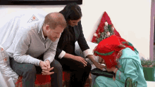 a man and a woman are sitting on a couch talking to a girl in a green dress .