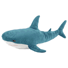 a purple stuffed shark with white teeth is laying on a white surface