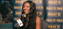a woman is smiling in front of a shay 's universe sign