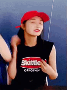 a woman wearing a red hat and a black shirt that says skittles on it