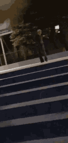 a man is walking across a street at night with a sign that says ' railway station ' on it