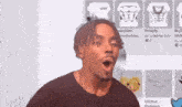 a man is making a funny face with his mouth open in front of a screen .