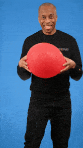 a man wearing a black shirt that says ghostbusters holds a red balloon in his hands