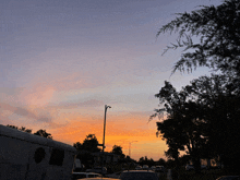 a sunset with a few cars parked in front of a building