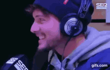 a man wearing headphones and a blue hat is talking into a microphone .