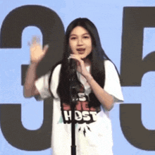 a woman is standing in front of a microphone wearing a shirt that says host