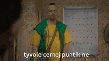 a man in a green vest and yellow shirt stands in front of a white board with the words tyvole cernej puntik ne on it
