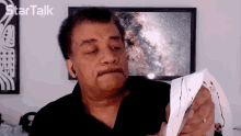 a man holds a piece of paper in front of a star talk advertisement
