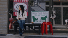 a woman sits on a bench in front of a dogs and cats sign