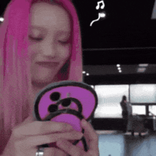 a woman with pink hair is holding a purple item in her hands .