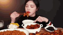 a woman is eating food with chopsticks and a bowl of noodles