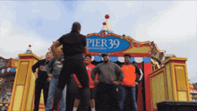 a group of people are posing in front of a pier 39 sign
