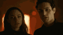 a man and a woman are standing next to each other in a dark room looking at each other .