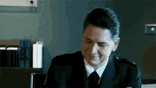 a man in a suit and tie is smiling while sitting at a desk in a dark room .