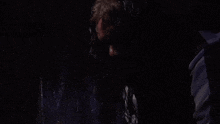 a man is standing in a dark room with water coming out of his face .