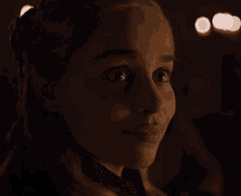 a close up of a woman 's face with a few lights in the background