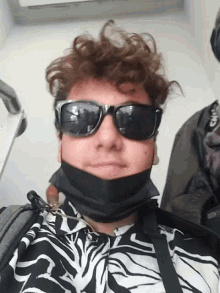 a man wearing sunglasses and a face mask looks at the camera