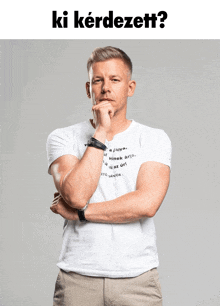 a man in a white t-shirt has his hand on his chin and the words ki kérdezett written above him