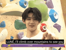 a young man is pointing at a climbing wall and says " lune "