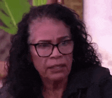a close up of a woman wearing glasses and a black jacket .