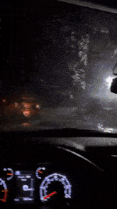 a car is driving down a road at night and the speedometer reads 20