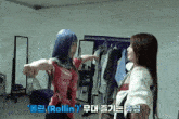 two women standing next to each other in a room with clothes hanging on a rack .