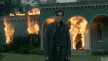 a man wearing a blindfold stands in front of a burning building with the letters амс on the bottom